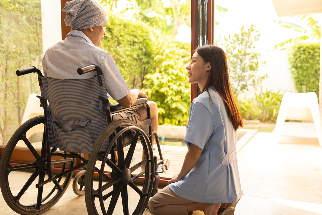 Young Nurse with Patient in a Wheelchair at Home 